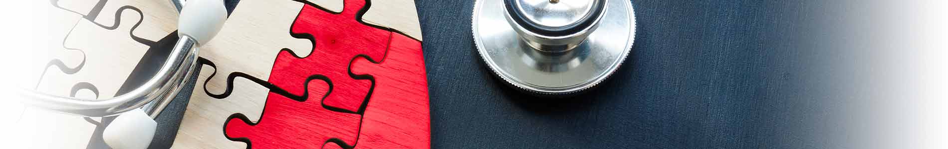 Plain-wooden puzzle pieces in shape of lungs with 2 red puzzle pieces representing cancer below a stethoscope