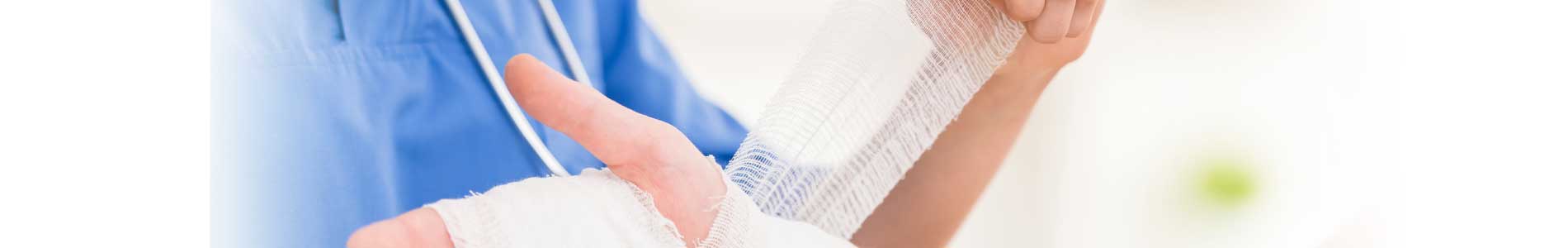 Nurse in blue scrubs and stethoscope taking care of wound on right arm of a patient by bandaging with gauze