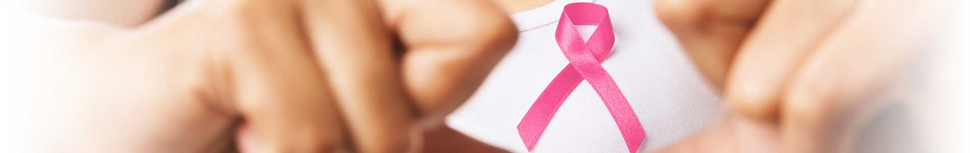 Woman in white tank top making a heart with her hands and holding pink ribbon for breast cancer awareness 